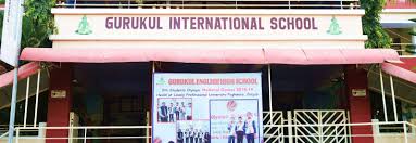 The Gurukul International School in Sikar welcomes visitors with a vibrant and inviting entrance featuring a prominent red canopy awning stretching across the front, boldly displaying "GURUKUL INTERNATIONAL SCHOOL" in large white letters, accented by small green tree-like motifs symbolizing growth and nature. Below the canopy hangs a large banner proclaiming "ENGLISH MEDIUM SCHOOL" along with "Gurukul International English School" and details about admissions for the new session, accompanied by a colorful group photo of uniformed students proudly posing together, likely highlighting achievements or school events. The main building facade combines warm red brick walls on the lower level with lighter upper sections, framed by metal railings on an upper balcony or walkway, while green foliage and potted plants add a fresh, eco-friendly touch to the entrance area. The overall setup exudes a disciplined yet nurturing atmosphere typical of a reputed CBSE-affiliated English medium institution, with the gateway area neatly maintained, steps leading to the entrance, and signage emphasizing quality education, making it an appealing and professional front for parents and students seeking holistic learning in Sikar.